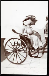 Una modelo de moda sentada en un carruaje sosteniendo una sombrilla, 1902